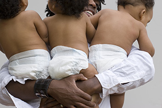 man holding triplets in his arms