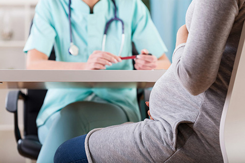 pregnant woman sitting with doctor